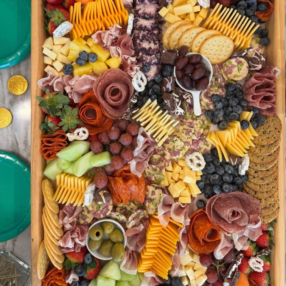 A large charcuterie board filled with cheeses, meats, fruits, crackers, and olives.