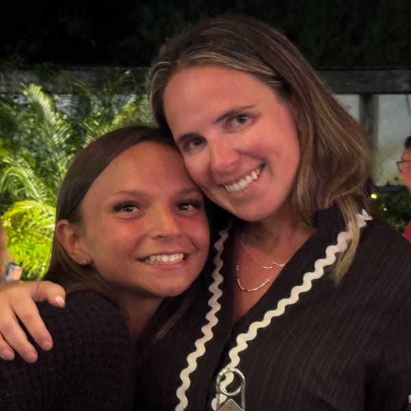Two smiling women, one with an arm around the other, pose closely together at The Salted Rim.