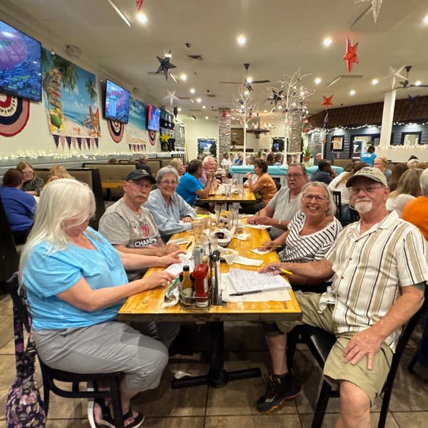 Diners seated at wooden tables in a lively restaurant, decorated with patriotic stars and beach murals.