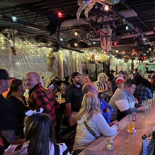 Patrons in costumes at The Salted Rim Margarita Bar & Grille, with Halloween decorations hanging from the ceiling.
