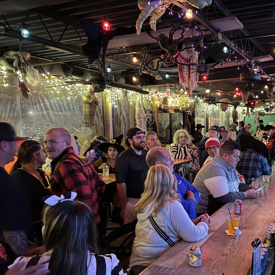 Patrons in costumes at The Salted Rim Margarita Bar & Grille, with Halloween decorations hanging from the ceiling.