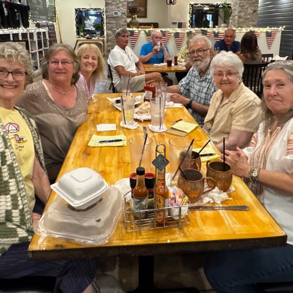 A group of six smiling people seated around a wooden table at The Salted Rim Margarita Bar & Grille.