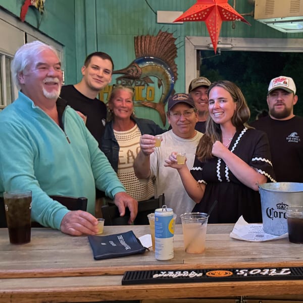 Group of six smiling people at The Salted Rim Margarita Bar & Grille, some holding up shot glasses.