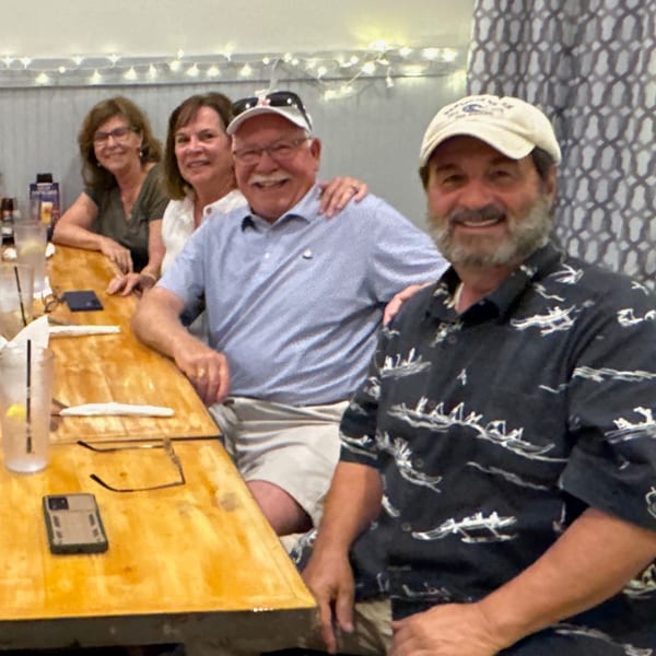 Four smiling customers, two men and two women, seated at a wooden bar inside The Salted Rim.
