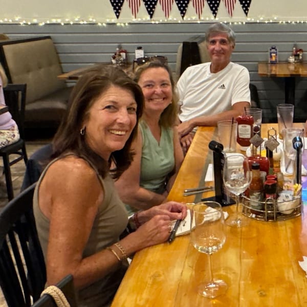 Three happy diners, two women and one man, seated at a wooden table in The Salted Rim.