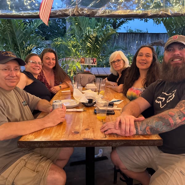 Six happy customers enjoying dinner and drinks at an outdoor table at The Salted Rim.