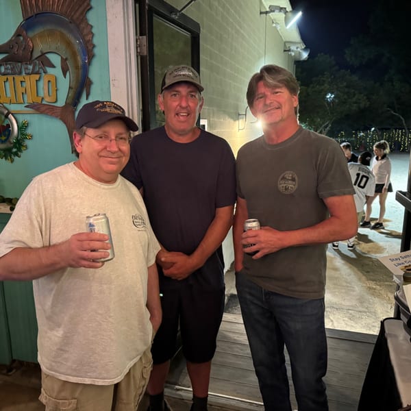 Three men holding drinks, smiling for a photo outside The Salted Rim Margarita Bar & Grille.